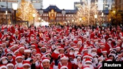 Peserta mengenakan kostum Santa Klaus berfoto sebelum membagikan hadiah dan membersihkan jalan untuk merayakan Natal di Tokyo, Jepang.