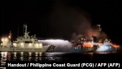 Penjaga Pantai Filipina menyemprotkan air ke kapal Lady Mary Joy 3 selama operasi pencarian dan penyelamatan di perairan Pulau Baluk-Baluk di Provinsi Basilan. (Foto: Philippine Coast Guard (PCG)/AFP)