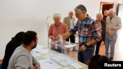 A man helps his mother to cast her vote at a polling station during local elections, in Ronda, southern Spain, May 28, 2023.