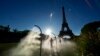 A spectator walks through mist sprayers on her way to Eiffel Tower Stadium to watch a beach volleyball match at the 2024 Summer Olympics, in Paris, France, July 28, 2024.