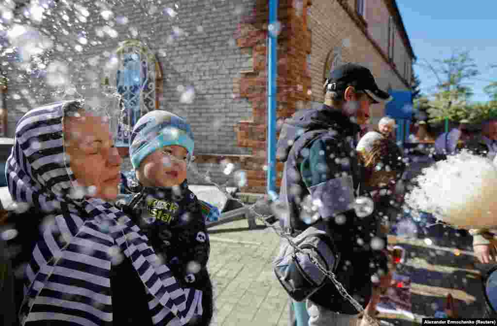 Las personas fueron rociadas con agua bendita cerca de la Catedral de San Nicolás en Mariupol, Ucrania controlada por Rusia, el 5 de mayo de 2024.