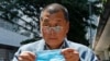 FILE - Hong Kong media tycoon Jimmy Lai, who founded local newspaper Apple Daily, is about to wear a face mask before entering a court in Hong Kong on May 5, 2020.