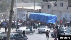 People chase behind a convoy of aid trucks driving into Gaza from Rafah crossing, Apr. 9, 2024. 