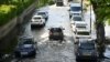 FILE - Cars are driven along a flooded road as the River Thames overtops the riverbank at high tide in London, Britain, April 19, 2023. 
