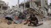 Dua pemuda Palestina duduk di depan sebuah bangunan yang rata setelah serangan udara Israel semalaman di Rafah di Jalur Gaza selatan, pada 9 Oktober 2023. (Foto: AFP)