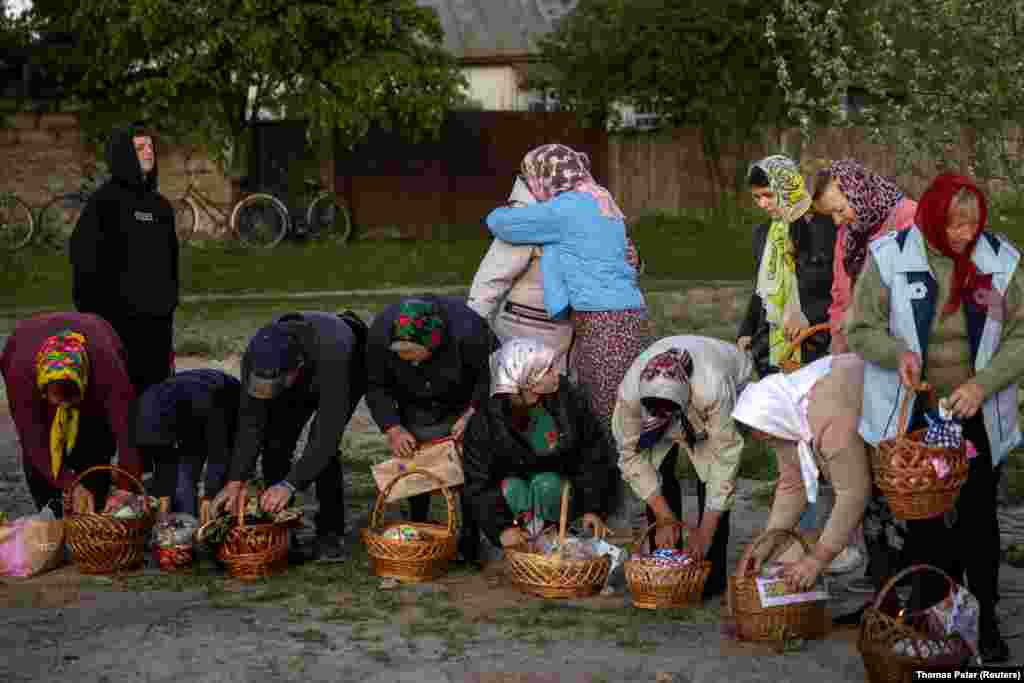 Los creyentes recogieron sus cestas de Pascua después que fueron bendecidas por un sacerdote durante un servicio en la aldea de Krasne, región de Chernihiv, Ucrania, el 5 de mayo de 2024.