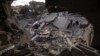 Palestinians inspect the rubble at the site of an airstrike that the Israeli military said targeted the house of an Islamic Jihad member, in Deir al-Balah, central Gaza Strip, May 13, 2023. 