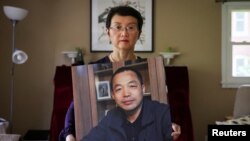FILE - Sophie Luo Shengchun, the wife of jailed Chinese human rights lawyer, Ding Jiaxi, poses with a photo of him at her home in Alfred, New York, July 28, 2022. 