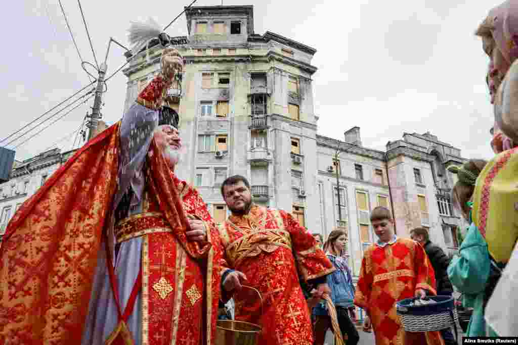 Un sacerdote roció agua bendita sobre los creyentes frente a un edificio residencial recientemente dañado por un ataque con misiles rusos, en Kiev, Ucrania el 5 de mayo de 2024.