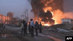 Sejumlah warga berkumpul di depan lokasi kebakaran di depot bahan bakar Conakry pada 18 Desember 2023. (Foto: AFP/Stringer)
