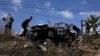 Palestinians gather around a car destroyed in a drone strike Zeita village, north of the West Bank city of Tulkarem, Aug. 3, 2024.