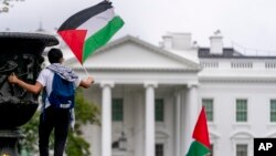 Seorang pria mengibarkan bendera Palestina dalam aksi pro-Palestina di Lafayette Square, di depan Gedung Putih, Washington, D.C., Sabtu, 14 Oktober 2023. (AP/Andrew Harnik)