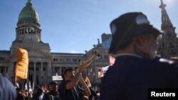 Un hombre toca una trompeta mientras estudiantes universitarios, sindicatos y grupos sociales argentinos se reúnen frente al Congreso Nacional para protestar contra los recortes de "motosierra" del presidente Javier Milei, en Buenos Aires, Argentina, el 23 de abril de 2024.