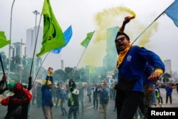Seorang buruh memegang alat pembuat asap saat mengikuti aksi protes terhadap Undang-Undang Cipta Kerja (omnibus law), di luar gedung Mahkamah Konstitusi, di Jakarta, 2 Oktober 2023. (REUTERS/Willy Kurniawan)