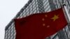 FILE - A building housing the PricewaterhouseCoopers (PWC) branch office stands behind a Chinese national flag in Beijing, Jan. 24, 2014. 