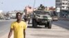 People walk past members of the Senegalese armed forces patrolling the streets in Dakar, on June 2, 2023, following violent protests.