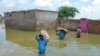 A family displaced by flood, carry their belongings as they wade through floodwaters after heavy monsoon rains at Sohbatpur in Jaffarabad district, Balochistan province, Pakistan, Aug. 19, 2024. 