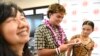 Lahainaluna High School 2024 graduate Talan Toshikiyo, center, stands by sister Taleah Toshikiyo and school college and career counselor Ginny Yasutake as he opens his scholarship announcement in the school's library July 31, 2024, in Lahaina, Hawaii. 
