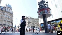 A Police officer stands at the scene in Leicester Square, as a man was arrested with the accusation of stabbing an 11-year-old girl and 34-year-old woman, in London, Aug. 12, 2024.
