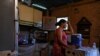 Gladys leans over a plastic containers that she fills daily with water through a community-made pipe system in the low-income neighborhood of Petare, in Caracas, Venezuela, May 12, 2023.