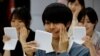 Students learn how to practice facial muscles with mirrors at a smile training course at Sokei Art School in Tokyo, Japan, May 30, 2023.