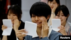Students learn how to practice facial muscles with mirrors at a smile training course at Sokei Art School in Tokyo, Japan, May 30, 2023.