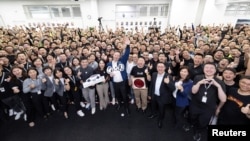 Tesla Chief Executive Officer Elon Musk, center, poses for a group photo at the Shanghai Gigafactory of the U.S. electric vehicle maker in Shanghai, in this handout image released on June 1, 2023. (Tesla/Handout via Reuters)
