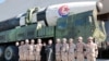 Pemimpin Korea Utara Kim Jong Un dan putrinya berfoto bersama sejumlah ilmuwan, pejabat militer dan insinyur yang terlibat dalam proyek uji coba rudal balistik antarbenua Hwasong-17 dalam foto yang yang dirilis pada 27 November 2022. (Foto: KCNA via Reuters)