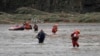In this photo released by Xinhua News Agency, rescuers walk across a river after delivering relief items to affected people on the other bank in Heishanke Township, the city of Huludao in Liaoning province, Aug. 21, 2024. 