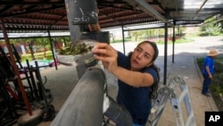 FILE - Abigail Lopez, a member of cooperative Pixcatl, removes a filter from a water collector system at a community garden in Mexico City, July 14, 2024. 