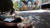 Un local cuenta notas de Bolívar venezolano frente a un mural que representa al difunto presidente venezolano Hugo Chávez en Caracas, Venezuela, 14 de marzo de 2019.