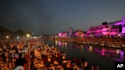 Orang-orang menyalakan lampu di tepi sungai Saryu di Ayodhya, India, Minggu, 23 Oktober 2022. Lebih dari 15.000.000 lampu tanah dinyalakan di sepanjang tepi Sungai Saryu, saat jutaan orang di seluruh Asia merayakan Diwali, umat Hindu Festival Lampu. (Foto AP/Rajesh Kumar Singh)