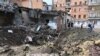 Warga lokal tampak mengamati reruntuhan bangunan yang hancur akibat serangan pasukan Rusia di Kharkiv, pada 11 Agustus 2022. (Foto: AFP/Sergey Bobok)