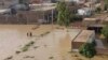 Warga mengarungi daerah yang dilanda banjir menyusul hujan lebat di distrik Charsadda di Khyber Pakhtunkhwa, Pakistan, 29 Agustus 2022. (Foto: AFP)