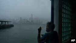 Seorang pria menarik tali pancing dari kawasan pejalan kaki Victoria Habour saat badai tropis Ma-on melewati Hong Kong, 25 Agustus 2022. (AP/Anthony Kwan)