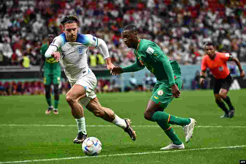 Attaquant ya Angleterre #07 Jack Grealish (G) azali kowelela ndembo na défenseur ya Sénégal #02 Formose Mendy na match ya 8e ya Mondial Qatar 2022 na stade Al-Bayt, Doha, 4 décembre 2022. (Photo by Anne-Christine POUJOULAT / AFP)