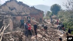 Penduduk desa Nepal berdiri di antara puing-puing rumah lumpur mereka setelah gempa bumi di distrik Doti, Nepal, Rabu, 9 November 2022. (Foto: AP)