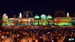 Warga menyaksikan pertunjukan cahaya di tepi sungai Sarayu pada malam Diwali, festival cahaya Hindu, di Ayodhya, 23 Oktober 2022. (SANJAY KANOJIA / AFP)