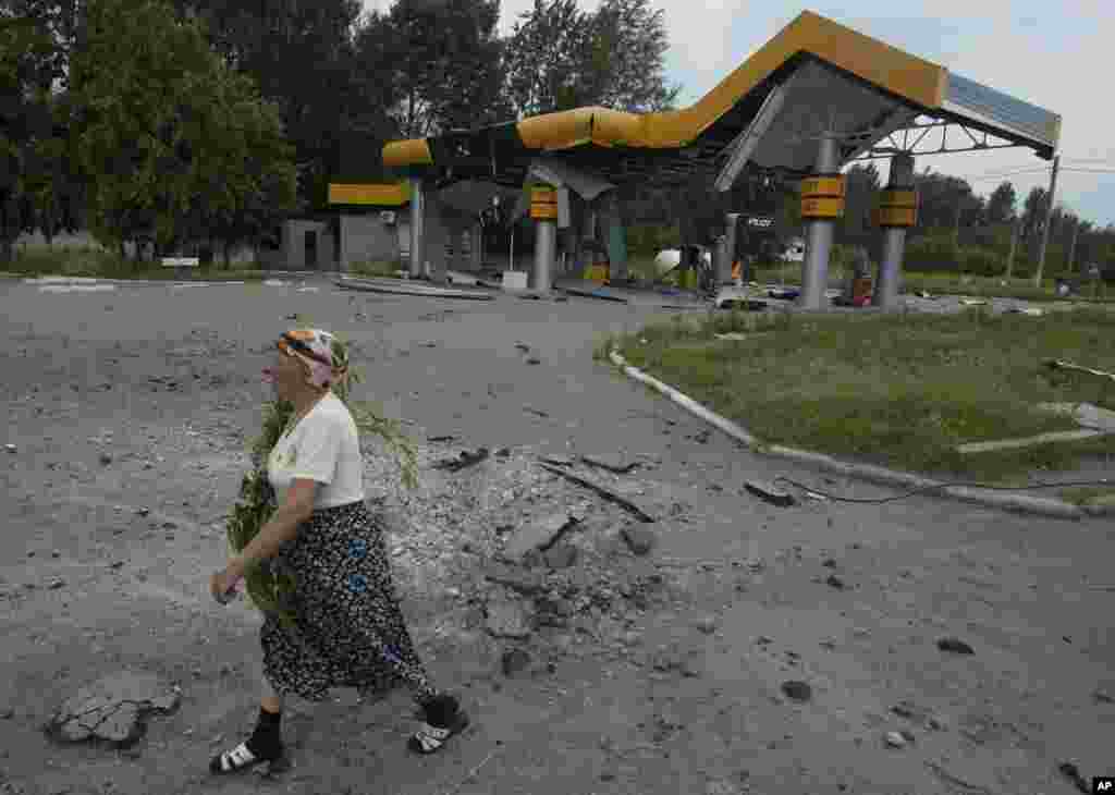 Жінка іде повз розбиту артилерією заправку. Слов&#39;янськ.