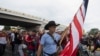 Seorang migran tampak membawa bendera AS ketika ia berjalan bersama rombongan migran lainnya dalam perjalanan dari Tapachula, Meksiko, menuju AS, pada 6 Juni 2022. (Foto: AP/Isabel Mateos)