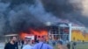Sejumlah warga menyaksikan asap yang keluar dari pusat perbelanjaan di Kota Kremenchuk, Ukraina, yang diserang oleh rudal milik pasukan Rusia pada 27 Juni 2022. (Foto: Viacheslav Priadko via AP)