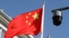Sebuah kamera pengintai keamanan yang menghadap ke jalan difoto di sebelah bendera China yang berkibar di Beijing, China 25 November 2021. (Foto: REUTERS/Carlos Garcia Rawlins)