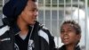 FILE - Tenjin, right, an 11-year-old Eritrean boy who arrived on a boat from Tripoli without his parents, waits with another young migrant at the port of Lampedusa to board a ferry bound for Porto Empedocle in Sicily, February 20, 2015. 