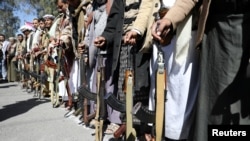 FILE - Houthi backers hold weapons during a protest outside the U.S. Embassy against the U.S. decision to designate the Houthis a foreign terrorist organization, in Sanaa, Yemen, Jan. 18, 2021. The designation is being revoked as of Feb. 16, 2021.