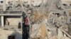 Seorang perempuan Palestina berdiri di ruangan yang hancur di sebuah gedung saat dia memeriksa lokasi serangan Israel di Khan Younis, selatan Jalur Gaza, 6 Desember 2023. (REUTERS/Ahmed GAMBAR Zakot)