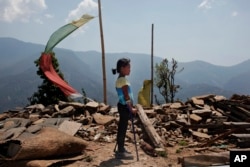 Khendo Tamang, 8, berdiri di dekat puing-puing rumah yang runtuh setelah gempa bumi melanda Banskharka, Nepal pada 25 April 2015. (Foto: AP)