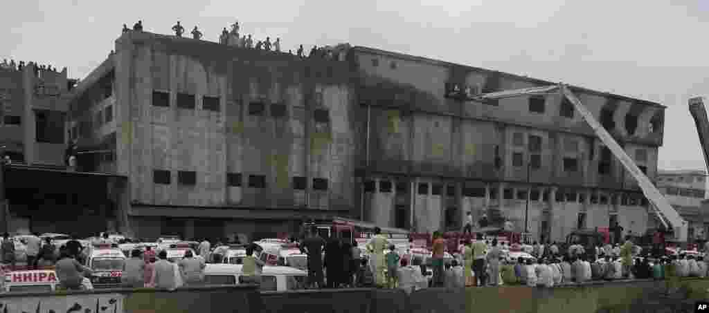 People gather as rescue work is in progress at a burnt garment factory in Karachi, Pakistan, September 12, 2012.