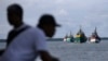 FILE - Fishing boats carrying recently rescued fishermen sail toward the town of Tual, Indonesia, Saturday, April 4, 2015. 