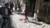 People inspect the damage as a civilian walks near blood stains at a market hit by air strikes in Aleppo's rebel-held al-Fardous district, Syria, Oct. 12, 2016. 