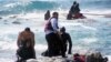 A man rescues an migrant from the Aegean sea, in the eastern island of Rhodes, April 20, 2015. 